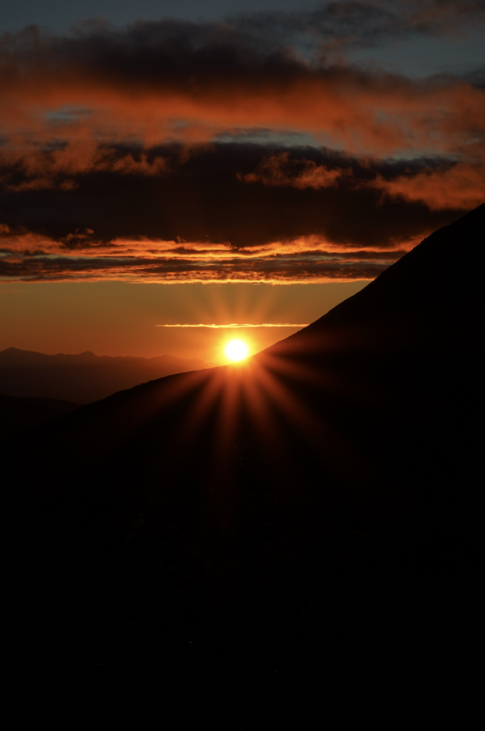 “Sunset glow over rugged Talkeetna Mountains in Hatcher Pass, Alaska, with silhouetted peaks and alpine tundra.”